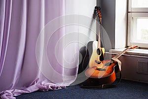 Two acoustic guitar next the window photo