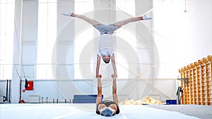 Two acrobats are practicing acrobatic handstand in gym. photo