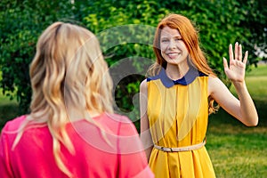 Two active cheerful girlfriends beautiful young ginger redhead irish girl in a yellow dress and european blonde woman in