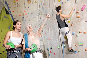 two active female marathon participants are standing in climbing hall