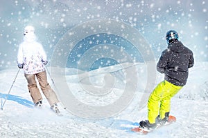 Two active friends skier and snowboarder ride on mountain top against blue snow sky and mountains. Ski resort concept