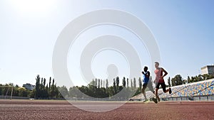 Two active runners competing at stadium, training hard to achieve sport success