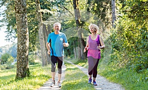 Two active seniors with a healthy lifestyle smiling while joggin