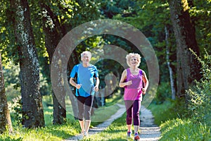 Two active seniors with a healthy lifestyle smiling while jogging