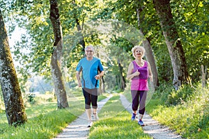 Two active seniors with a healthy lifestyle smiling while jogging together