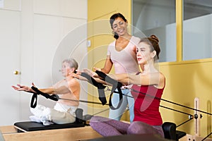 Two active women perform exercises on a simulator