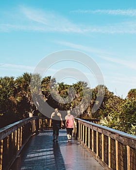 Two active women walk the boardwalk in New Smyrna Beach, Florida