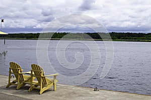 Two Adirondack chairs on a deck overlooking Lake