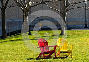 Two adirondack chairs, one yellow and the other one, red on the Carnegie Mellon campus