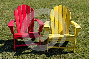 Two adirondack chairs, one yellow and the other one, red on the Carnegie Mellon campus
