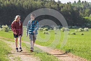 Two adolescents, a girl, and a boy, walk, explore, and enjoy nature