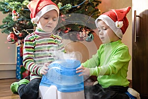 Two adorable boys playing with working humidifier, waiting for x-mas