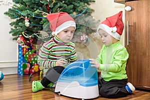 Two adorable boys playing with working humidifier, waiting for x-mas