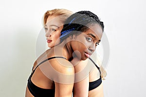 two adorable caucasian and afro women leaned on each other hugging