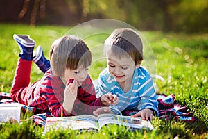 Two adorable cute caucasian boys, lying in the park in a fine su