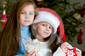 Two adorable girls in front of christmas tree