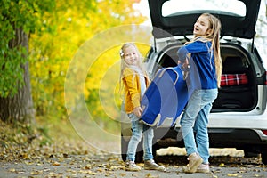 Two adorable girls with a suitcase going on vacations with their parents. Two kids looking forward for a road trip or travel. Autu