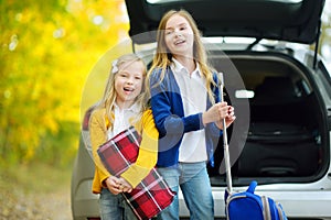 Two adorable girls with a suitcase going on vacations with their parents. Two kids looking forward for a road trip or travel. Autu