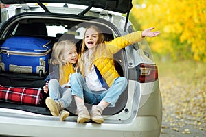 Two adorable girls with a suitcase going on vacations with their parents. Two kids looking forward for a road trip or travel. Autu