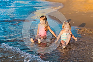 Two adorable kids playing in the sea on a beach