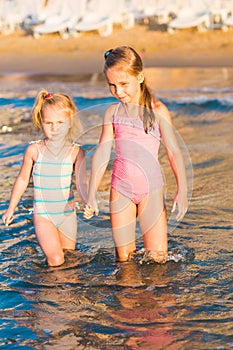 Two adorable kids playing in the sea on a beach