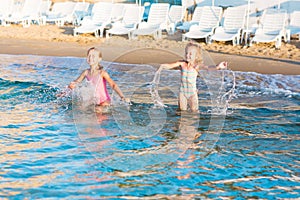 Two adorable kids playing in the sea on a beach