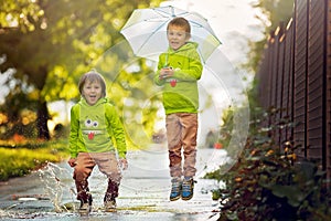 Two adorable little boys, playing in a park on a rainy day, play