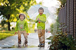 Two adorable little boys, playing in a park on a rainy day, play