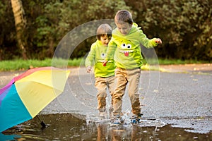 Two adorable little boys, playing in a park on a rainy day, play