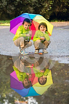 Two adorable little boys, playing in a park on a rainy day, play