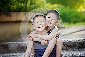 Two adorable little brothers laughing and hugging on warm and sunny day