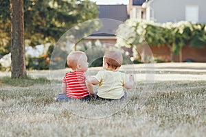 Caucasian babies sitting together in field meadow outside