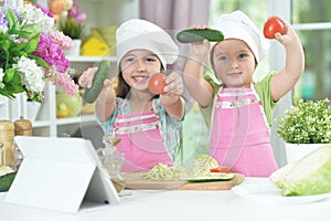 Two adorable little girls in aprons having fun