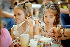 Two adorable little girls are eating at family picnic on summer day.