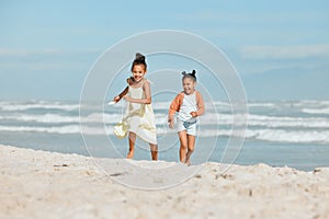 Two adorable little mixed race girls running and having fun at the beach. Two sibling sisters playing on the shore