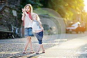 Two adorable little sisters having fun together on warm and sunny summer evening in Desenzano del Garda town, Italy