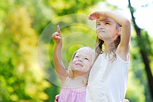 Two adorable little sisters pointing at a plane on the sky