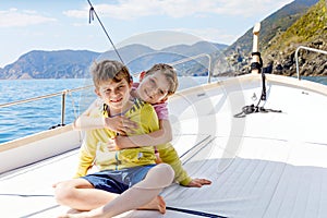 Two adorable school kid boys, best friends enjoying sailing boat trip. Family vacations on sea on sunny day. Children