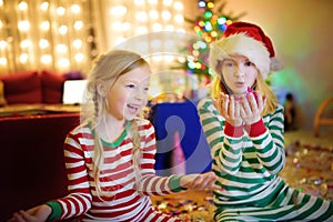 Two adorable sisters celebrating New Years eve in beautifully decorated room at home.