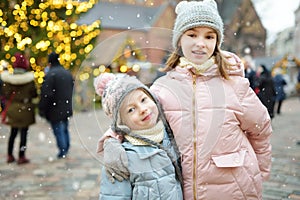 Two adorable sisters having a good time together on traditional Christmas fair in Riga, Latvia. Children enjoying sweets, candies