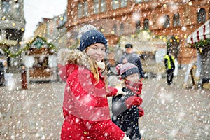 Two adorable sisters having a good time together on traditional Christmas fair in Riga, Latvia. Children enjoying sweets, candies