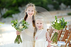 Two adorable young bridesmaids holding beautiful flower bouquets after wedding cemerony outdoors