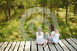 Two adorable young girls catching babyfrogs in summer forest