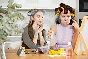 Two adult besties applying facial mask at home together