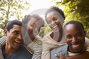 Two adult black couples have fun piggybacking, close up