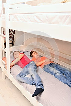 Two adult boys sleep dressed on the bed