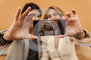 Two adult caucasian beautiful ladies on walk with phones take selfie while sitting on street.