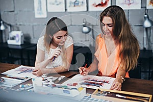 Two adult female students working on their paintings studying at art school