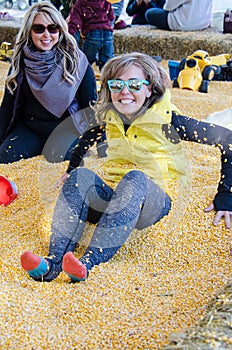Two adult females bury each other in a corn pit at a corn maze