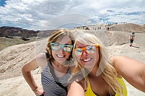 Two adult females take a selfie while at Zabriskie Point lookout in California Death Valley National Park